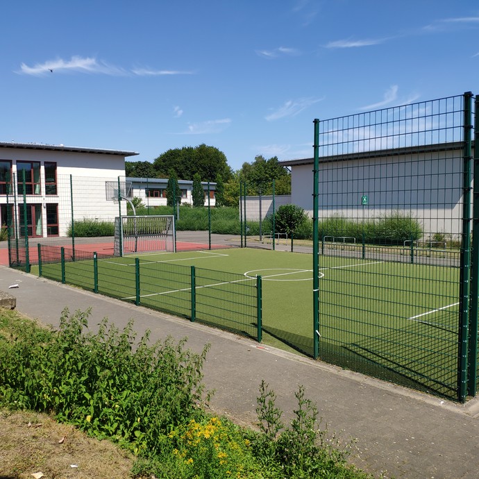 Ein umzäunter Kunstrasenplatz zum Fußballspielen. (vergrößerte Bildansicht wird geöffnet)